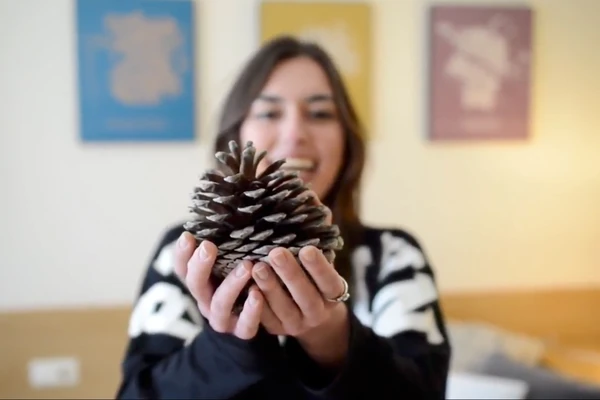 Trabajo de Imppulsa, agencia de marketing digital en Pamplona: fotograma del spot «Efecto piña» de la Residencia Universitaria El Huerto, una estudiante sostiene una piña con las dos manos